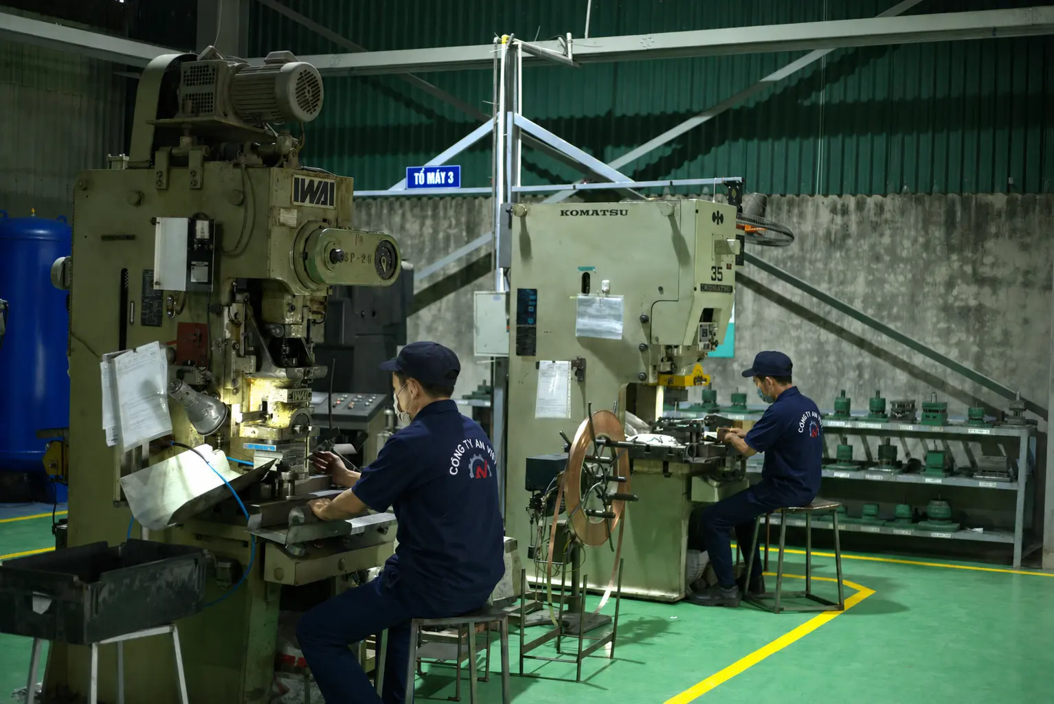 製造現場でプレス機を運転するAn Vietの作業者2名